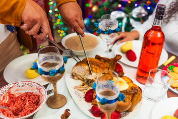 Hands carving roast turkey at a family Christmas dinner, surrounded by festive dishes, wine and Christmas decorations, creating a warm and cozy atmosphere at the Christmas celebration. 