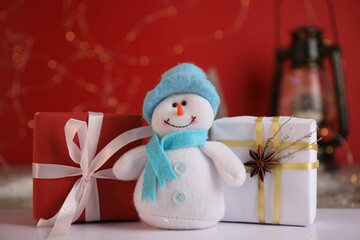 Funny snowman figure and Christmas gifts on white table