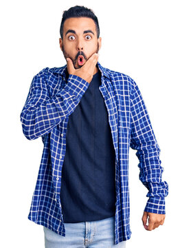 Young hispanic man wearing casual clothes looking fascinated with disbelief, surprise and amazed expression with hands on chin