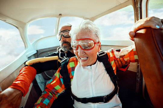 Senior woman preparing to skydive with instructor in airplane