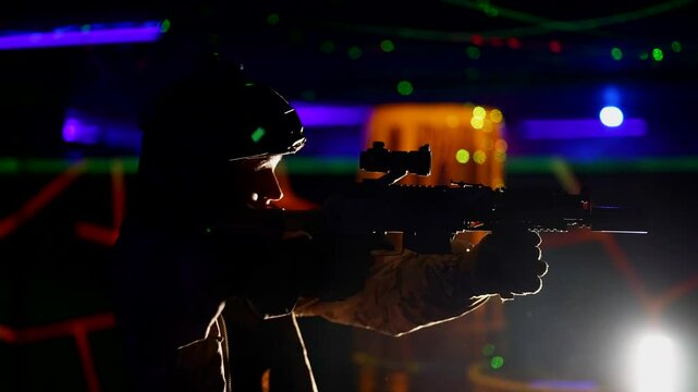 A camouflaged woman with a microphone on her helmet stands surrounded by lasers and neon lights. The atmosphere seems fantastic and battle-ready.