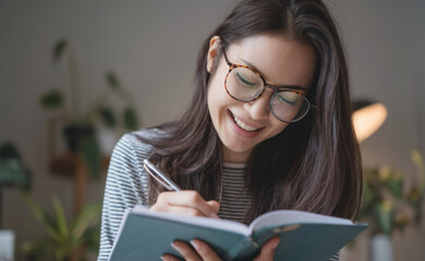 Happy woman writing diary. Woman smiling, writing in a notebook, expresses happiness and positivity.