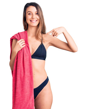 Young beautiful girl wearing bikini and beach towel pointing finger to one self smiling happy and proud