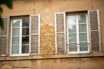 Weathered shuttered windows on rustic stone building exterior