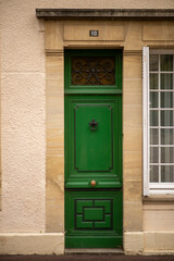 Naklejka premium Elegant green door with ornate knocker and decorative glass panel