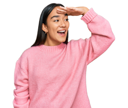 Young asian woman wearing casual winter sweater very happy and smiling looking far away with hand over head. searching concept.