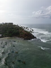 Stunning aerial view of Mirissa, Sri Lanka: a tropical paradise with palm-fringed beaches, vibrant blue waters, and picturesque coastline under clear, sunny skies.