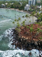 Stunning aerial view of Mirissa, Sri Lanka: a tropical paradise with palm-fringed beaches, vibrant blue waters, and picturesque coastline under clear, sunny skies.
