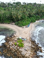 Stunning aerial view of Mirissa, Sri Lanka: a tropical paradise with palm-fringed beaches, vibrant blue waters, and picturesque coastline under clear, sunny skies.