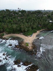 Stunning aerial view of Mirissa, Sri Lanka: a tropical paradise with palm-fringed beaches, vibrant blue waters, and picturesque coastline under clear, sunny skies.
