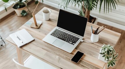 Fototapeta premium A laptop, phone, cup of coffee, notebook and a pencil holder with pencils are on a wooden table.
