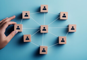 A hand connects wooden blocks representing individuals in a network, illustrating collaboration and communication concepts.