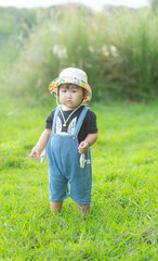 Little Caucasian girl, 1 year old, wearing casual clothes, running on the green grass in the park, spending time outdoors in the village,A young girl