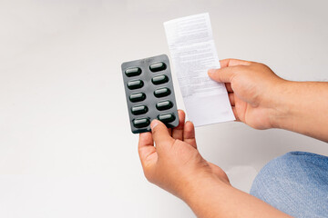 close up of a person reading a prescription, prescription while holding a blister pack of medicine pills