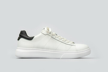 White leather sneakers isolated on gray background. Fashionable stylish sports casual shoes. Creative minimalistic layout with footwear.