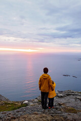 Family with children and pet, hiking Sukkertoppen trail on Senja island, Norway