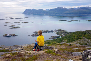 Family with children and pet, hiking Sukkertoppen trail on Senja island, Norway