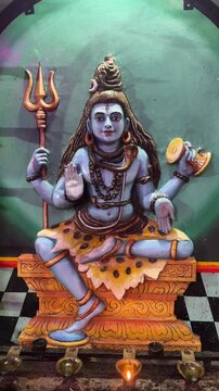 4K clip of hindu god Shiv colorful idol at south indian temple with clay diya lightening for the prayer.