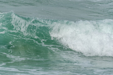 Wave of the green and blue Atlantic Ocean at the edge of a beach in the Iroise Sea.