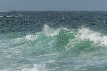 Wave of the green and blue Atlantic Ocean at the edge of a beach in the Iroise Sea.