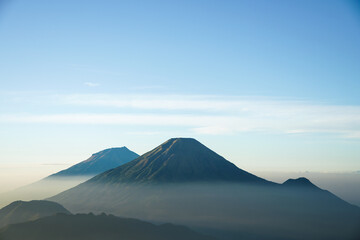 Fototapeta premium Mount Sindoro and Sumbing seen afar from Mount Prau with blue sky and white clouds in Dieng, Wonosobo, Indonesia.