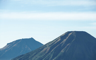 Mount Sindoro and Sumbing seen afar from Mount Prau with blue sky and white clouds in Dieng, Wonosobo, Indonesia.