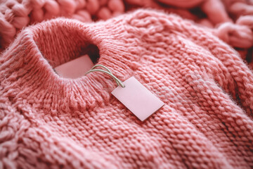 Pink wool sweater with an empty inner label on the neck. Blank laundry care clothes label on knitted fabric background, mockup, blank space to place text or brand logo, size and info patch on clothes