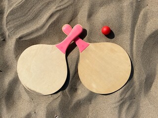 The rackets and the ball of a beach tennis set lies in the sand on the beach