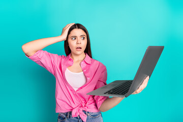 Photo portrait of attractive teen woman hold netbook frightened dressed stylish pink clothes cyan on blue color background