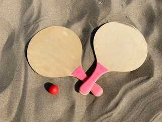 The rackets and the ball of a beach tennis set lies in the sand on the beach