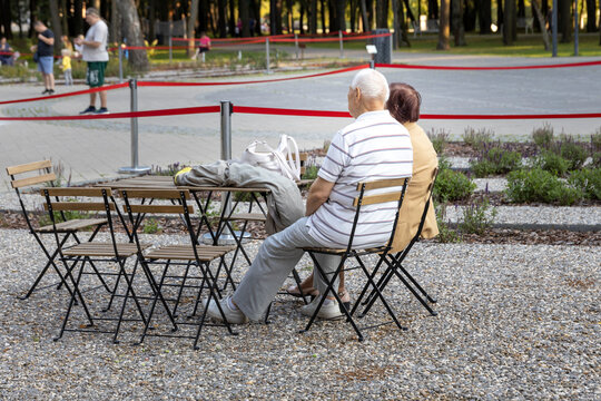A couple of older people are sitting at a table in a park