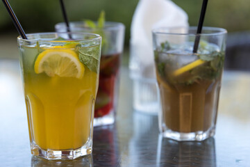 Three glasses of drinks on a table, one of which is a lemonade