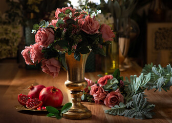 Beautiful golden vases with artificial flowers and pomegranates, on wooden table, household items, retro