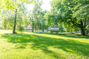 A park with a large green field and a wagon in the middle