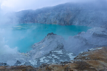 Breathtaking view of turquoise crater lake, volcanic landscape, misty atmosphere