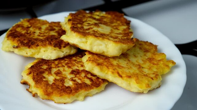 Cooked fried fresh potatoes pancakes, draniki on plate on kitchen at home. Preparing fresh dish. Cuisine, culinary, recipe. Traditional Russian food on lunch dinner fry on vegetable oil.