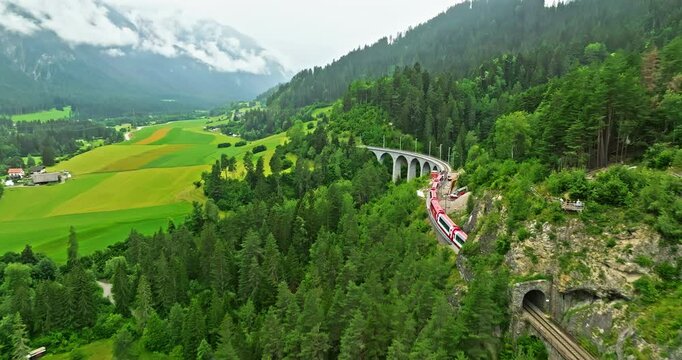 Railway scenic route in Switzerland. Express red swiss train in Swiss Alps. Landwasser Viaduct world heritage sight with luxury Glacier and Bernina express summer scenery