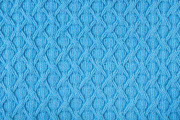 Knitted blue background. Large knitted fabric with a pattern. Close-up of a knitted blanket