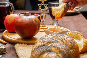 Challah, honey, pomegranate apple and wine on a table with a menorah in honor of Rosh Hashanah