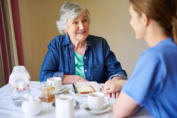 Breakfast, nurse and smile of old woman in dining room of retirement home for assisted living together. Conversation, food or visit with caregiver and happy senior in apartment for diet or nutrition