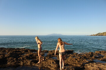 Girls walking around rock pools in New Zealand