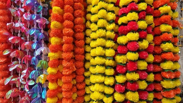 Multicolour artificial flowers (used for Diwali and Ganesh festival decoration, rangoli designs) hanging inside a shop, on the day before Diwali festival and Ganesh Festival.