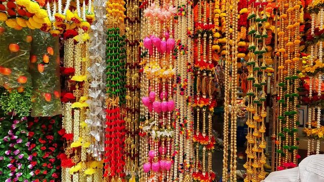 Multicolour artificial flowers (used for Diwali and Ganesh festival decoration, rangoli designs) hanging inside a shop, on the day before Diwali festival and Ganesh Festival.