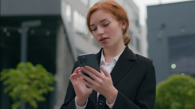 Young Caucasian girl business woman female student businesswoman using mobile phone holding cellphone device online app client ordering taxi checking message browsing social media outdoors city office