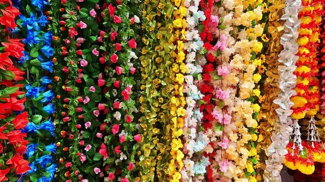 Multicolour artificial flowers (used for Diwali and Ganesh festival decoration, rangoli designs) hanging inside a shop, on the day before Diwali festival and Ganesh Festival.