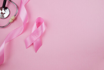 Fototapeta premium Top view photo of pink ribbon symbol of breast cancer awareness and stethoscope on isolated pastel pink background with copyspace