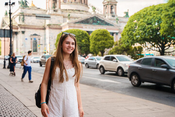 Young girl with long hair standing near St. Isaac's Cathedral in St. Petersburg. The concept of the tourist season, an active pastime. Saint Petersburg, Russia - 16 July 2024