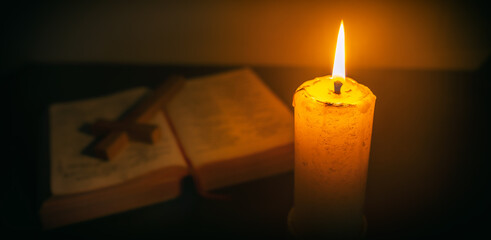 Candle on wooden table with the Bible and cross in the night. worship prayer and bible study concept.