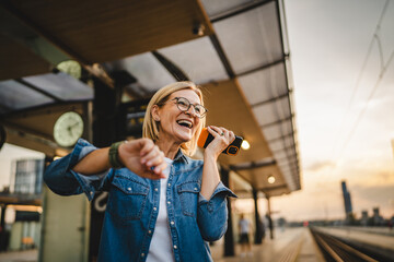 Mature woman wait for the train and record voice mail on mobile phone