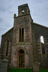 A weathered stone church in a peaceful village is detailed, showing its architecture and a somber tombstone, evoking history and reverence.